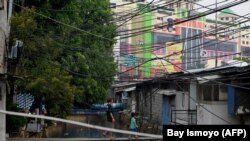 Seorang pria dan anak laki-laki melintasi jembatan kecil buatan masyarakat yang tinggal di bantaran sungai di Jakarta pada 26 November 2019. (Foto: AFP/Bay Ismoyo)