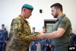 Predsednik Ukrajine Volodimir Zelenski dodeljuje odlikovanje vojniku na ceremoniji obeležavanja Dana mornaričkih snaga u Odesi. (Fot: Pres služba ukrajinskog predsednika / AFP)