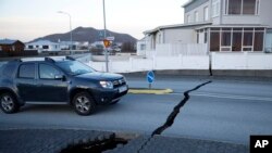 A car drives toward a fissure in a road in the town of Grindavik, Iceland, Nov. 13, 2023 following seismic activity.
