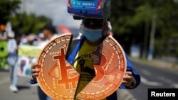 ARCHIVO - Una persona sostiene carteles de Bitcoin en una protesta contra la reelección del presidente de El Salvador, Nayib Bukele. En San Salvador, el 15 de septiembre de 2023.