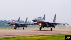 FILE - In this undated photo released by China's Xinhua news agency, two Chinese SU-30 fighter jets take off from an unspecified location to fly a patrol over the South China Sea.