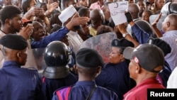 FILE - Police officers stand guard as voters wait outside a polling station on the day of the presidential election, in Kinshasa, the Democratic Republic of Congo December 20, 2023. 