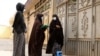 FILE - Afghan woman health workers wait by the door outside a house to administer Oral poliovirus vaccines (OPV) to the residing children during an immunisation campaign in Herat, May 15, 2023.