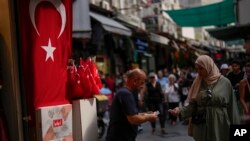 FILE - A vendor does business with a customer in a street market in Istanbul, Turkey, on Sept. 6, 2023. Turkey's central bank delivered another huge interest rate hike on Nov. 23, 2023, which has left households struggling to afford food and other basic goods