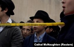 Anak laki-laki berdoa di luar sinagoga Tree of Life setelah penembakan pada Sabtu di sinagoge di Pittsburgh, Pennsylvania, AS, 29 Oktober 2018. (Foto: REUTERS/Cathal McNaughton)