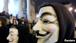 Участники протестов в маске Гая Фокса, символизирующей группу хактивистов Anonymous, принимают участие в митинге в центре Брюсселя 28 января 2012 года
