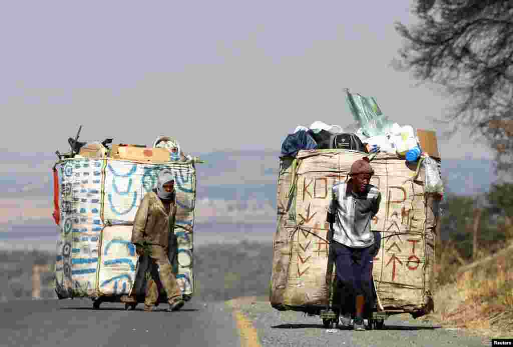 Steven Lesoona and Thabang Pule, waste pickers, pull trolleys loaded with recyclable materials in Naturena, near Johannesburg, South Africa, July 3, 2023.