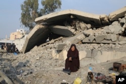 A Palestinian woman displaced by the Israeli bombardment of the Gaza Strip sits outside a destroyed home in Rafah, Dec. 27, 2023.