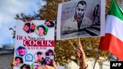 ফাইল ছবি—ইরানী র‍্যাপার তুমাজ সালেহির ছবি সম্বলিত (ডানে) এবং ইরানে নিহত শিশুদের ছবি সম্বলিত প্ল্যাকার্ড উঁচিয়ে ইরানীদের পক্ষে আয়োজিত বিক্ষোভে অংশ নিচ্ছে তুরস্কের মানুষ (২৬ নভেম্বর, ২০২২) 