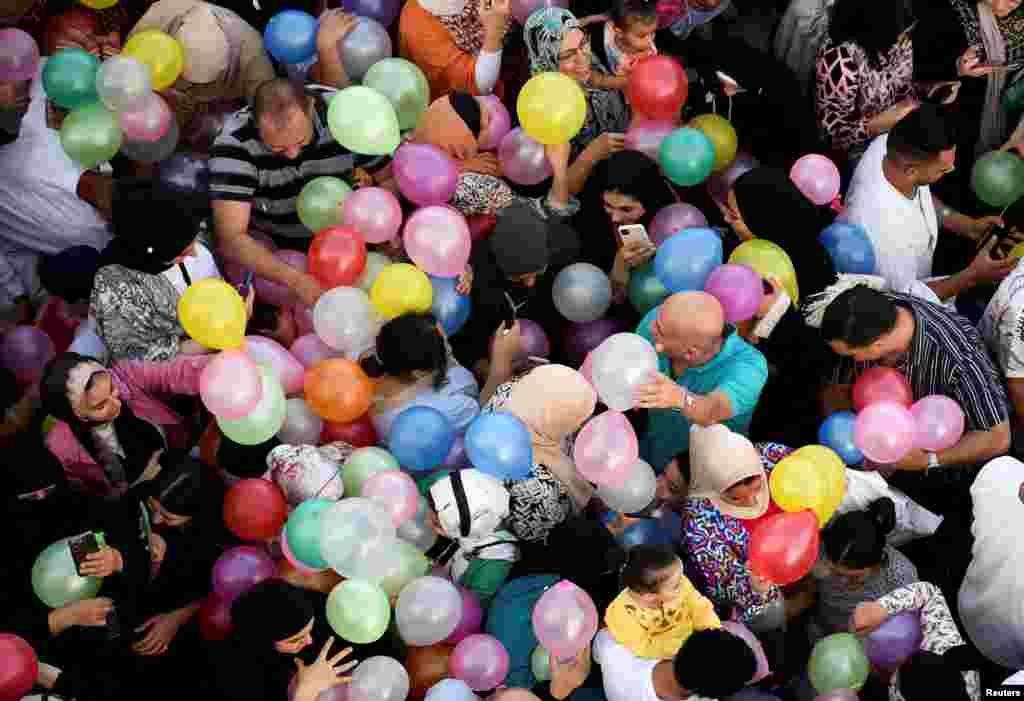 People attempt to catch balloons released after an Eid al-Adha prayer at a public park, outside El-Seddik Mosque in Cairo, Egypt