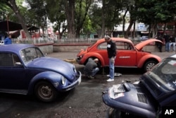 Volkswagen Beetle taxi drivers change a flat tire in the Cuautepec neighborhood of Mexico City, Friday, June 21, 2024. (AP Photo/Aurea Del Rosario)