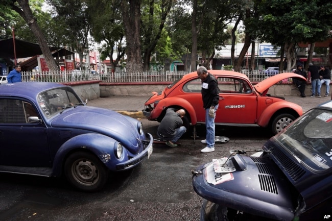 Volkswagen Beetle taxi drivers change a flat tire in the Cuautepec neighborhood of Mexico City, Friday, June 21, 2024. (AP Photo/Aurea Del Rosario)