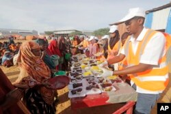 LSM setempat menyiapkan makanan berbuka puasa untuk warga di kamp pengungsi internal di pinggiran Mogadishu, Somalia, Jumat, 24 Maret. (AP/Farah Abdi Warsameh)