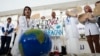 A woman pretends to resuscitate the Earth during a demonstration at the COP28 UN Climate Summit, Dec. 3, 2023, in Dubai, United Arab Emirates.