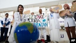 A woman pretends to resuscitate the Earth during a demonstration at the COP28 UN Climate Summit, Dec. 3, 2023, in Dubai, United Arab Emirates.