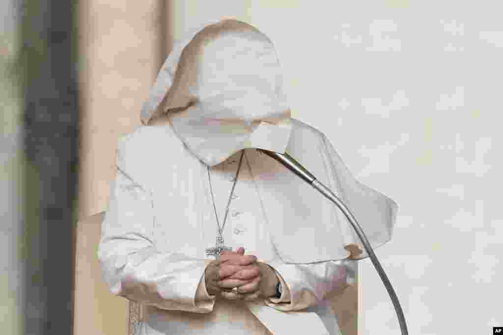 Hembusan angin meniup jubah Paus Fransiskus dan menutupi wajahnya, saat ia berpidato dalam audiensi umum mingguan di Lapangan Santo Petrus, Vatikan. (AP)&nbsp;