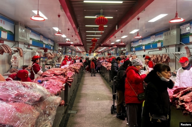 北京新发地农产品批发市场的肉类摊主在卖猪肉。(2024年2月2日)