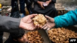 A customer buys a desert truffle from a merchant in a market in Syria's rebel-held northern city of Raqqa on March 14, 2023.