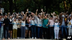 Students wave as French President Emmanuel Macron arrives at Sun Yat-sen University in Guangzhou, China, April 7, 2023. (Pool photo via AP)