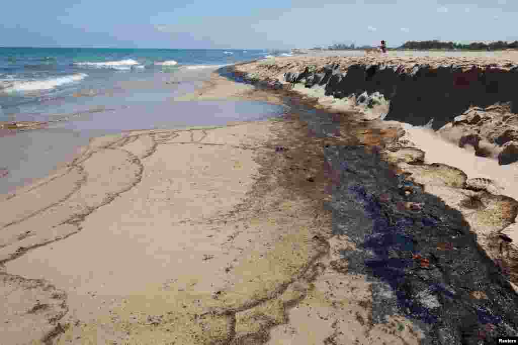 Pemandangan menunjukkan tumpahan minyak di pantai El Saler di Taman Alam Albufera di kota Valencia, Spanyol. Pihak berwenang menutup tiga pantai di pantai Mediterania karena dugaan tumpahan bahan bakar yang menyebar di pasir. (Reuters)