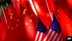 FILE - U.S. and Chinese flags are displayed together in Beijing on Sept. 16, 2018. An American cybersecurity firm says a Chinese hacking group that has been linked to attacks on U.S. state government computers is still “highly active."