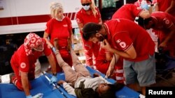 Tim medis dari organisasi palang merah tampak memeriksa seorang migran di Pulau Lampedusa, Italia, pada 14 September 2023. (Foto: Reuters/Yara Nardi)