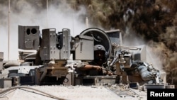 An Israeli soldier looks on as a military vehicle maneuvers near the Israel-Gaza border, amid the Israel-Hamas conflict, in Israel, July 10, 2024.