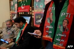 Pendukung mantan perdana menteri Pakistan Imran Khan mengenakan syal dengan gambar partainya Pakistan Tehreek-e-Insaf (PTI) di kantor PTI Khan di Islamabad pada 3 Februari 2024. (Foto: AFP)