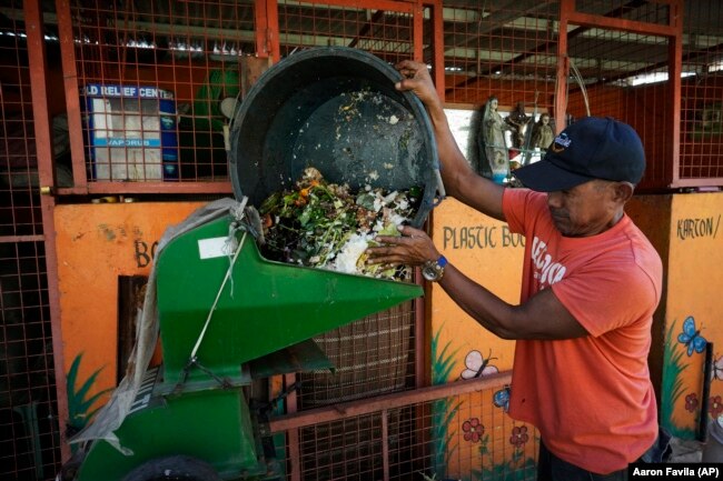 A worker pours garbage on a machine at a recycling facility in Malabon, Philippines on Monday Feb. 13, 2023. (AP Photo/Aaron Favila)