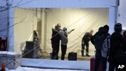 FILE - Royal Canadian Mounted Police, left, search migrants after their arrival at a reception center for irregular borders crossers, in Saint-Bernard-de-Lacolle, Quebec, in Canada, Jan. 12, 2022, in a photo taken from Champlain, N.Y.