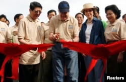 FILE - Former U.S. president Jimmy Carter cuts a ribbon next to his wife Rosalynn Carter (2nd R) during the inauguration of the New Life Community at Oudong village in Kandal province, 50 km (31 miles) north of Phnom Penh, November 21, 2009.