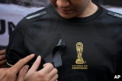 Seorang aktivis memasang pita hitam di dadanya saat unjuk rasa menentang pembatalan FIFA U-20 World Cup, di Jakarta, Jumat, 31 Maret 2023. (Foto: AP)