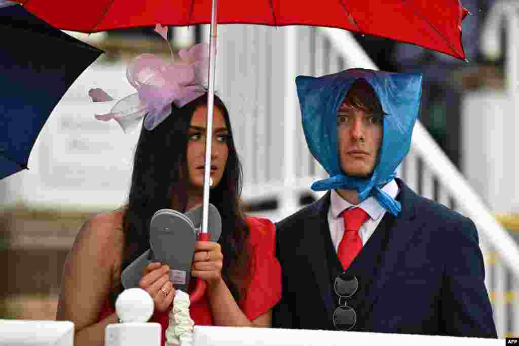Racegoers shelter from the rain as they attend the second day of the Grand National Festival horse race meeting at Aintree Racecourse in Liverpool, north-west England.