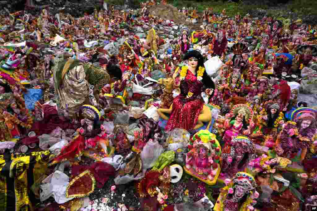 A woman searches for reusable material amid idols of Hindu goddess Dashama that were left by devotees on the banks of the Sabarmati River, in Ahmedabad, India.