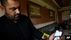 Jassem Ismail shows photos of his two children who were killed when a car they were in was hit by a planted explosive earlier this month, in his home in Muqdadiyah, Iraq, March 22, 2023. It is not known who carried out the attack.