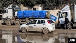 A United Nations vehicle moves past trucks carrying humanitarian aid entering the Gaza Strip through the Kerem Shalom (Karm Abu Salem) border crossing in the southern part of the Palestinian territory, Jan. 29, 2024.