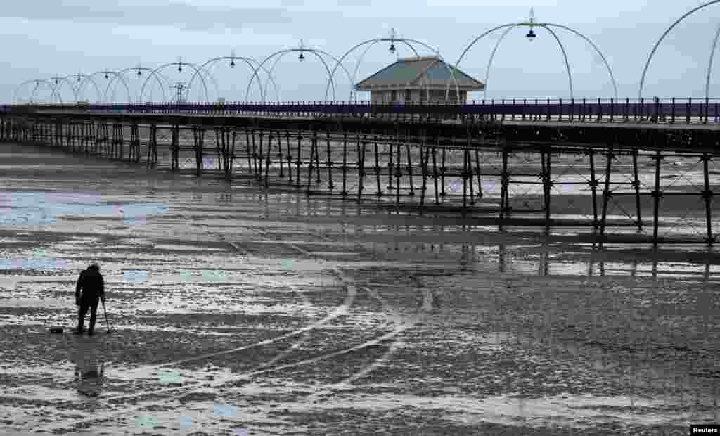 A man uses a metal detector on the beach in front of Southport Pier in Southport, Feb. 20, 2024. Britain&rsquo;s second longest pier has been closed for over a year for safety and structural reasons with the local council unable to fund the estimated &pound;13 million ($16 million) repair bill.