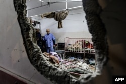 FILE - People inspect the damage in a room following Israeli bombardment at Nasser hospital in Khan Yunis in the southern Gaza Strip on Dec. 17, 2023.