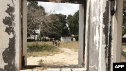 FILE - Children are seen through a broken window on September 30, 2022 in the port city of Palma where fighters affiliated to the Islamic State group attacked months prior. 