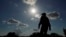 FILE - Kayak and canoe outfitter Jessie Fuentes walks along the Rio Grande under a warm sun, July 6, 2023. As the heat breaks records, weakening and sickening people, dire heat waves inspire effective efforts to prevent heat illness. 