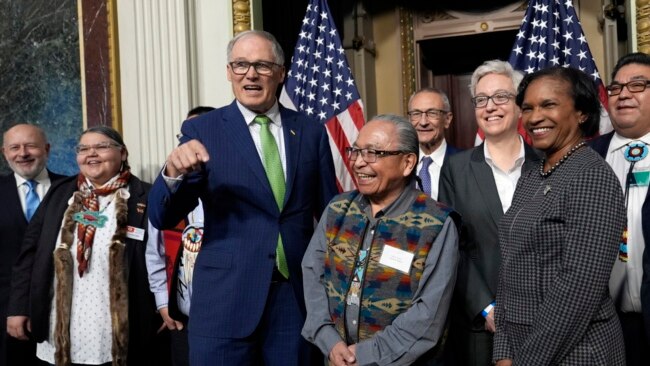 Washington Gov. Jay Inslee, third left, stands with Gerry Lewis of the Yakama Nation, fourth left, after a ceremony in Washington, Feb. 23, 2024. The Biden administration, four tribes and two governors launched a plan to help Pacific Northwest salmon.