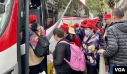 大批戴上旅行团鲜红色鸭舌帽的中国大陆旅客，吃完中饭后登上旅游巴离开土瓜湾 (美国之音/汤惠芸)