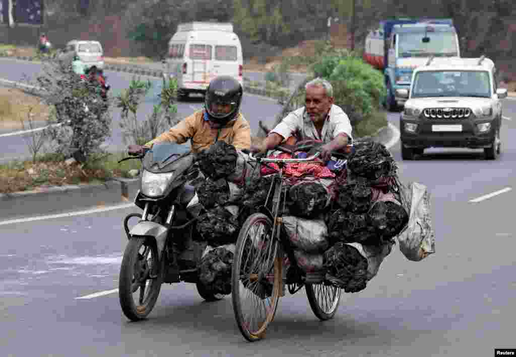 A motorcyclist pushes a man on a bicycle loaded with coal bags on the outskirts of Ranchi, India.