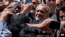 Reformist candidate in Iran's presidential election Masoud Pezeshkian is greeted by his supporters as he arrives to vote at a polling station in Shahr-e-Qods near Tehran, Iran, July 5, 2024. 