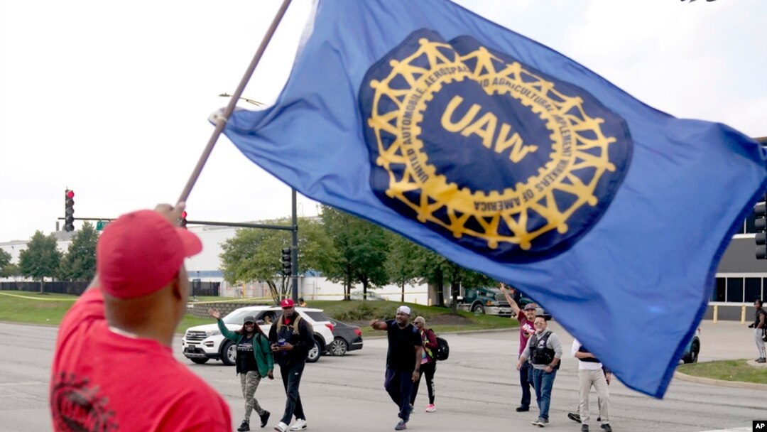 Members of the United Auto Worker Union walk out of the Chicago Ford Assembly Plant as Lance Williams from Lansing, Ill., waves the UAW flag Sept. 29, 2023, in Chicago.