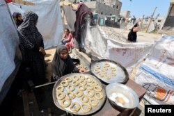 Sebuah keluarga pengungsi Palestina membuat kue tradisional saat mereka mempersiapkan hari raya Idul Fitri di kamp pengungsi Rafah, Jalur Gaza selatan.