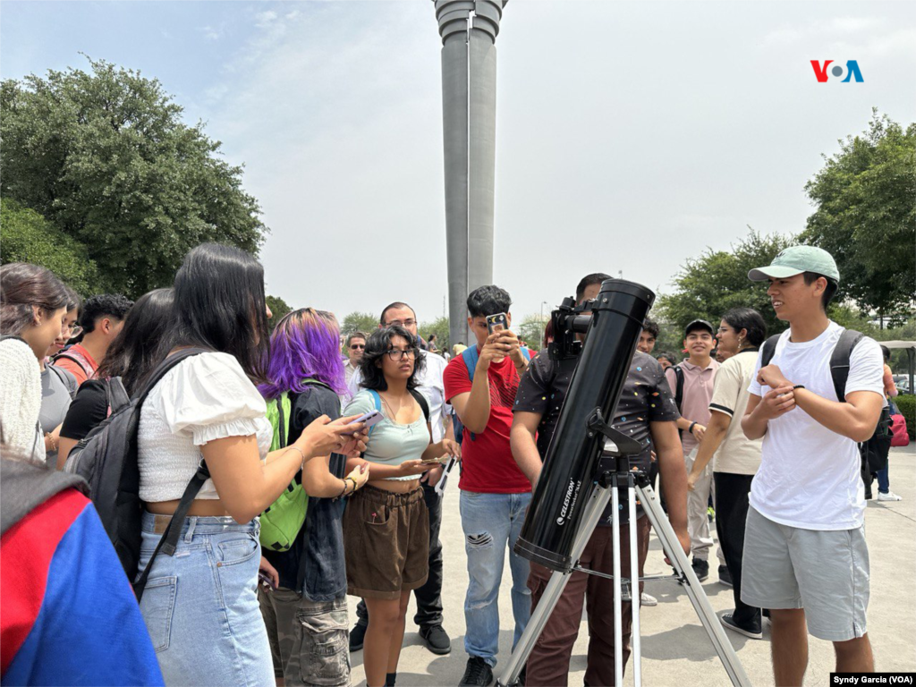 Un grupo de personas observa el eclipse de sol en una pantalla de un telescopio de un estudiante universitario mexicano.