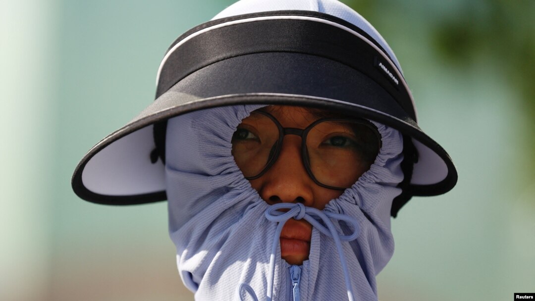 Seseorang mengenakan alat pelindung matahari di tengah gelombang panas yang menerpa Ibu Kota Beijing, China, 30 Juni 2023. (Foto: REUTERS/Tingshu Wang)