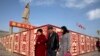 Sejumlah warga berjalan kaki melintasi patung Mao Zedong di Kashgar di bagian barat Wilayah Xinjiang, China, 4 November 2024. (Foto: Ng Han Guan/AP Photo)