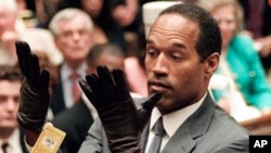 O.J. Simpson mengangkat tangannya di hadapan juri setelah mengenakan sepasang sarung tangan baru yang mirip dengan sarung tangan berdarah yang terkenal itu selama persidangan pembunuhan ganda di Los Angeles. (Foto: via AP)